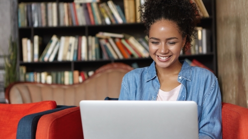 young woman smiling while looking at laptop computer