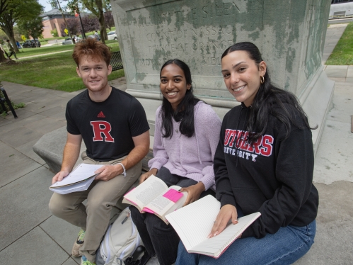 Rutgers students sitting at the base of Willie the Silent statue
